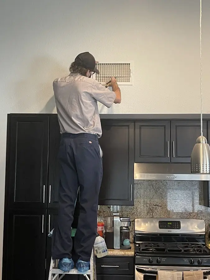Technician inspecting an air vent during HVAC service in Owings Mills
